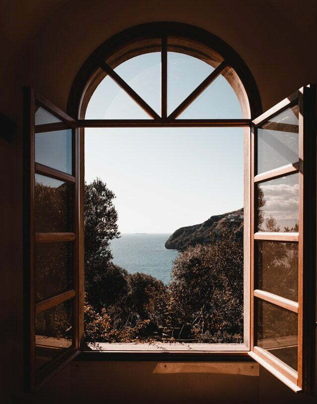 Ein halbrundes Fenster steht offen. Draußen ist eine Landschaft aus Bäumen und Wasser zu sehen