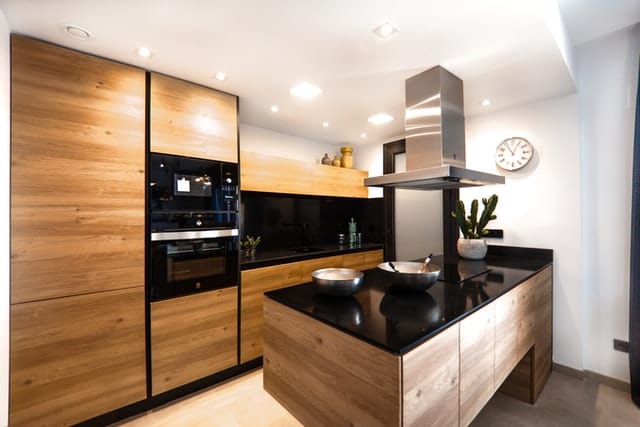 Küchenfronten aus Holz mit einer schwarz glänzenden Arbeitsplatte