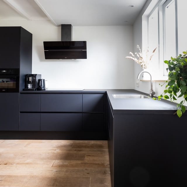 Eine schwarze Küche auf einem Holzboden