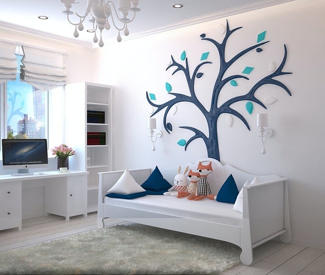 Ein Kinderzimmer mit weißen Möbeln und einem blauen Baum an der Wand