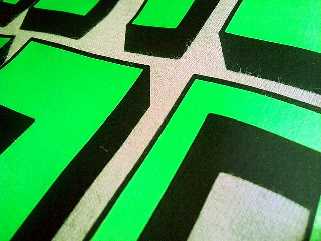 Grüne und Schwarze Formen sind auf einem grauen T-Shirt gedruckt