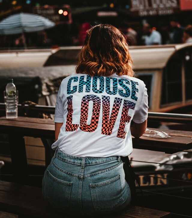 Eine Frau steht mit dem Rücken zum Betrachter. Auf Ihrem T-Shirt steht groß Choose Love