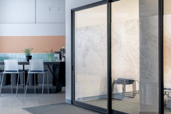 Perfekt für moderne Büros: Glas-Trennwände Ein Raum ist durch eine Glastür mit Dekorfolie abgetrennt