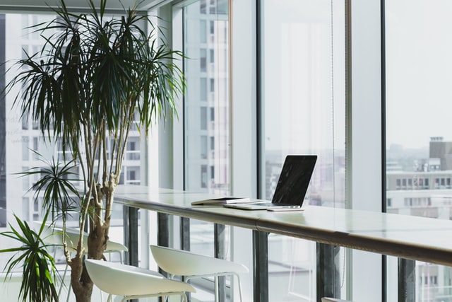 Ein Laptop steht auf einem Tisch direkt vor einem Fenster