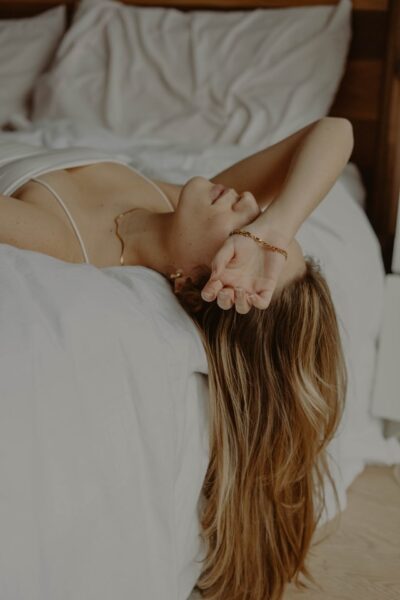 Eine Frau liegt auf einem Bett und hält sich einen Arm vor die Augen