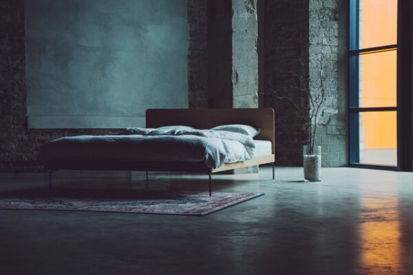 Schlaf beeinflusst die Gesundheit Ein großes Schlafzimmer mit wandhohen Fenstern und einem Bett darin