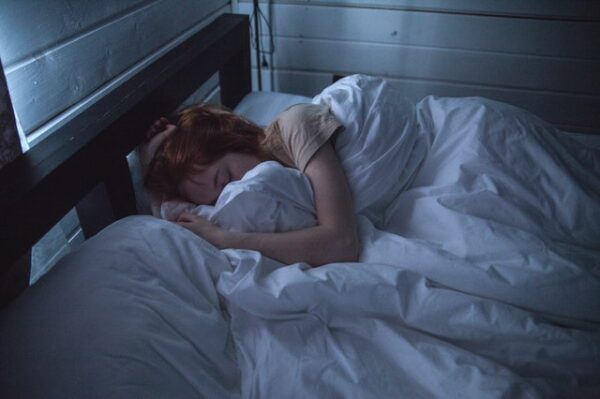 Eine Frau liegt eingekuschelt in ein weißes Bett