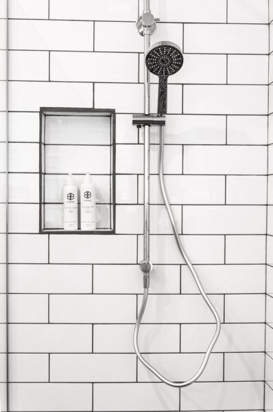 Eine an der Wand, vor weißen Fliesen montierte Dusche