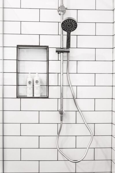 Wird zum kleinen Traumbad – mit Fliesenfolie Eine an der Wand, vor weißen Fliesen montierte Dusche