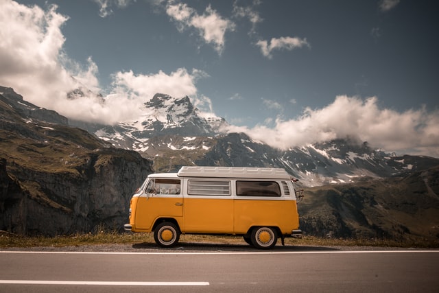 Ein weiß-gelbes Wohnmobil steht vor einer Gebirgskulisse