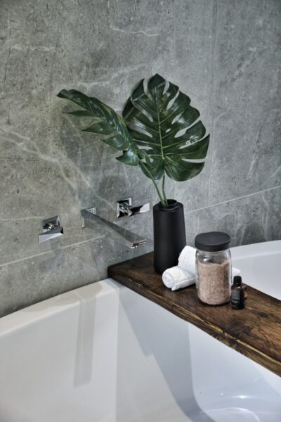 Schick und modern: Minimalistisch das Bad dekorieren Auf einem Wannentablett steht eine schwarze Vase und einige weitere Deko