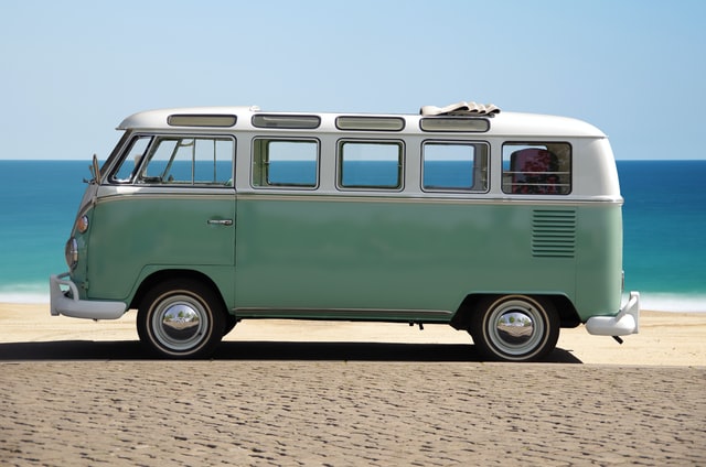 Ein mintfarbenes Wohnmobil steht am Strand