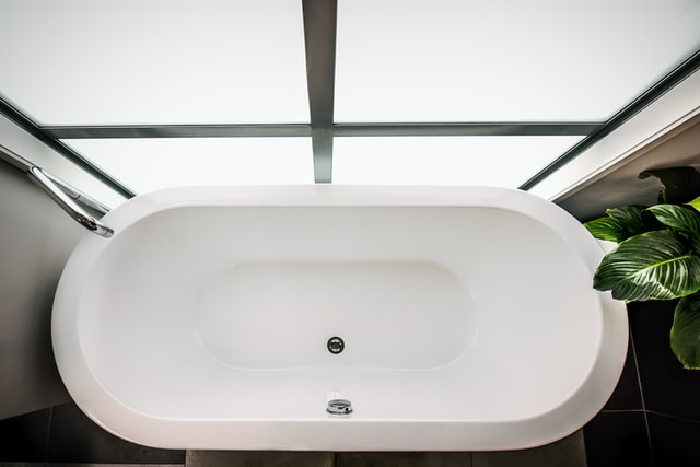 Eine Badewanne steht vor einem Fenster mit Milchglasfolie