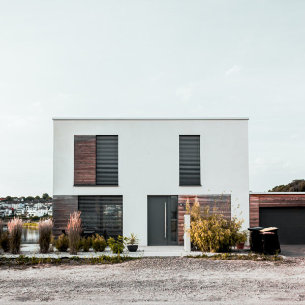 Wo am besten mit dem Haus Dämmen beginnen? Ein modernes Haus mit großen Fenstern und Fensterläden