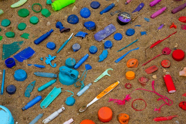 Verschiedenfarbige Plastikteile liegen sortiert am Strand