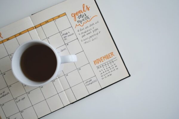 Strukturieren Sie Ihren Alltag sinnvoll Ein Kalender auf dem eine Tasse Kaffee steht