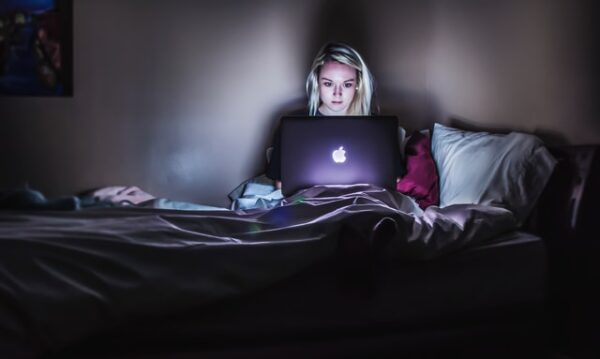 Jemand sitzt im Bett vor einem Laptop