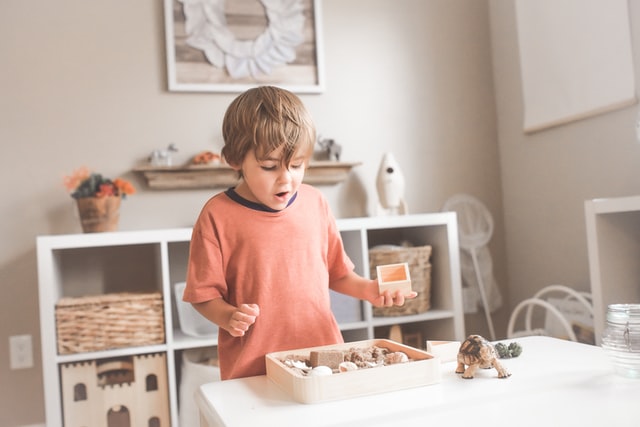 Kleiner Junge spielt mit Spielzeug nach niedrigem Tisch