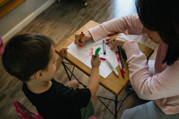 Zwei Kinder malen auf einem kleinen Tisch