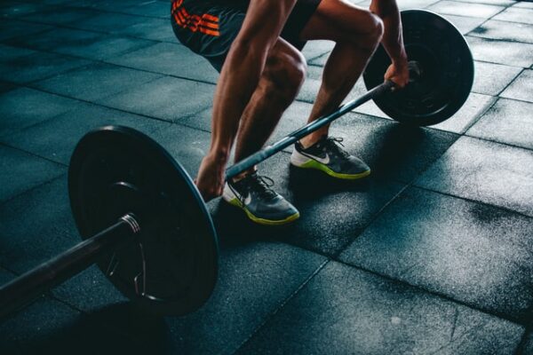 Die Kosten beim Fitnessraum einrichten sind nicht zu unterschätzen Mann hebt Gewichte