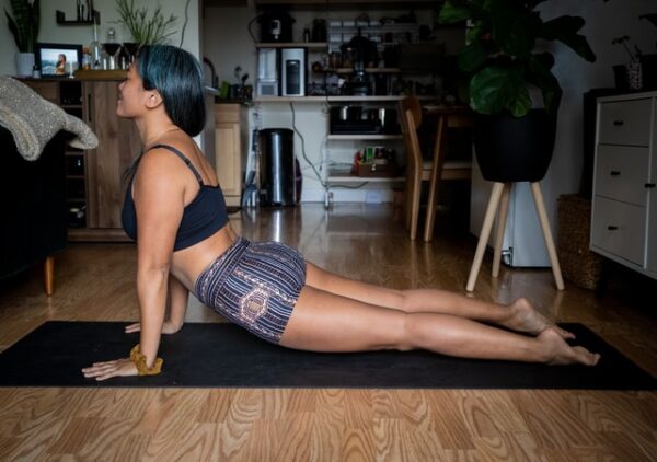 Frau macht Yoga in ihrer Wohnung