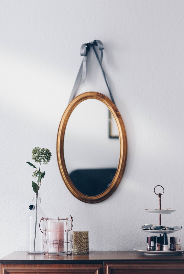 Ein ovaler Spiegel hängt über einer Kommode.