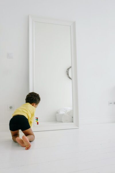 Ein kleines Kind spielt vor einem Spiegel