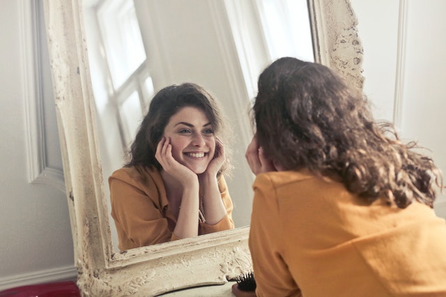 Frau lächelt sich im Spiegel an