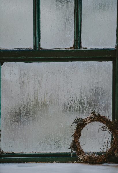 Ein altes, beschlagenes Fenster mit einem Kranz davor