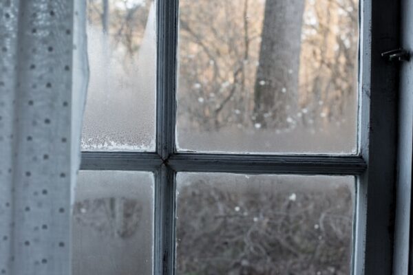 Ein beschlagenes Fenster mit einem Vorhang davor