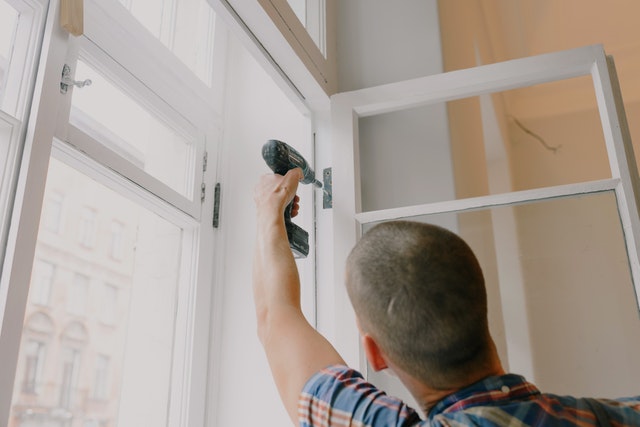 Ein Mann schraubt ein Fenster an