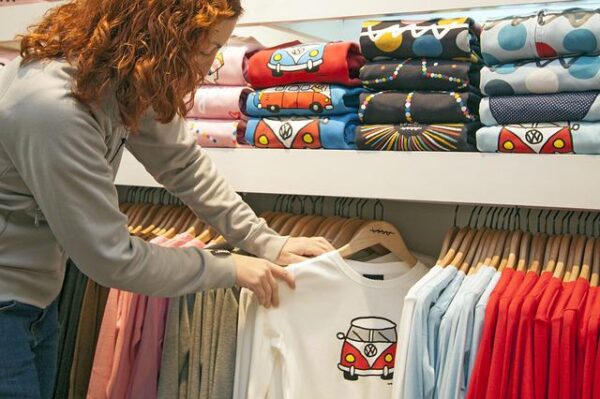 Mit Flex- und Flockfolie Kleidung gestalten Frau in einem Geschäft schaut sich bedruckte Pullover an