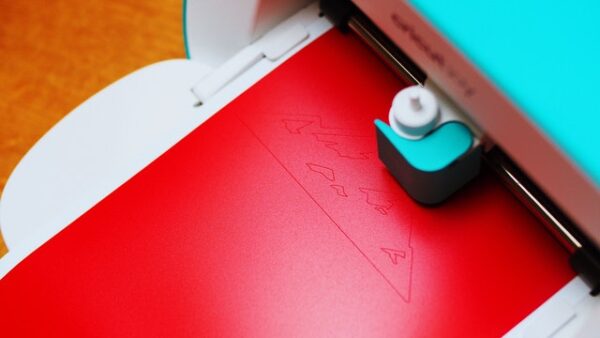 Der Schneideplotter – ein cleveres Gerät Schneideplotter von oben, der gerade aus roter Folie ein Bergmotiv ausschneidet