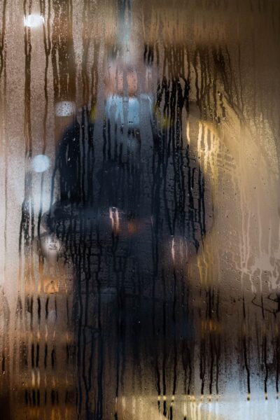 Kondenswasser an Scheiben kann nervig sein Person steht hinter einem beschlagenen Fenster