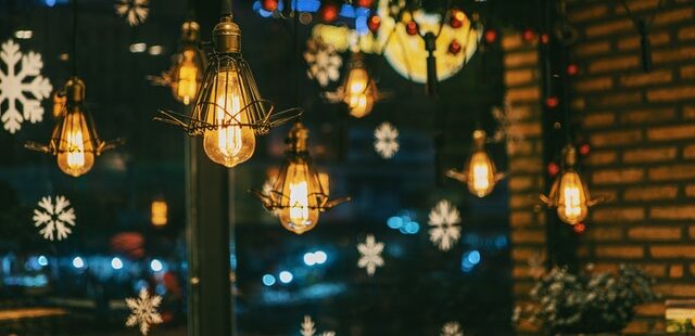Vor einem mit Papierschneeflocken beklebten Fenster hängen Lampen