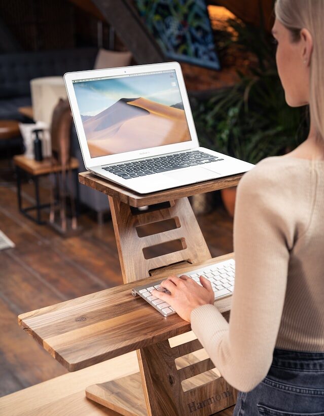 Eine Frau hat ihren Laptop auf einem verstellbaren Tisch aus Holz