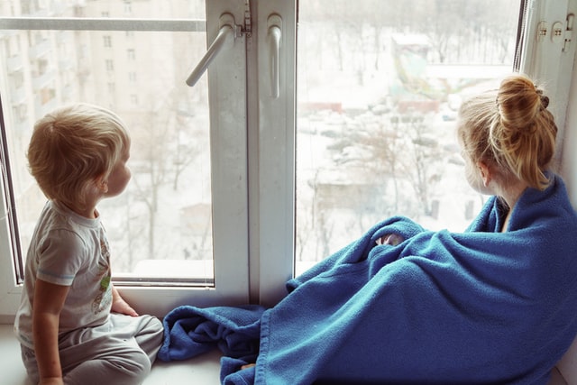 Zwei Kinder sitzen am Fenster und schauen hinaus