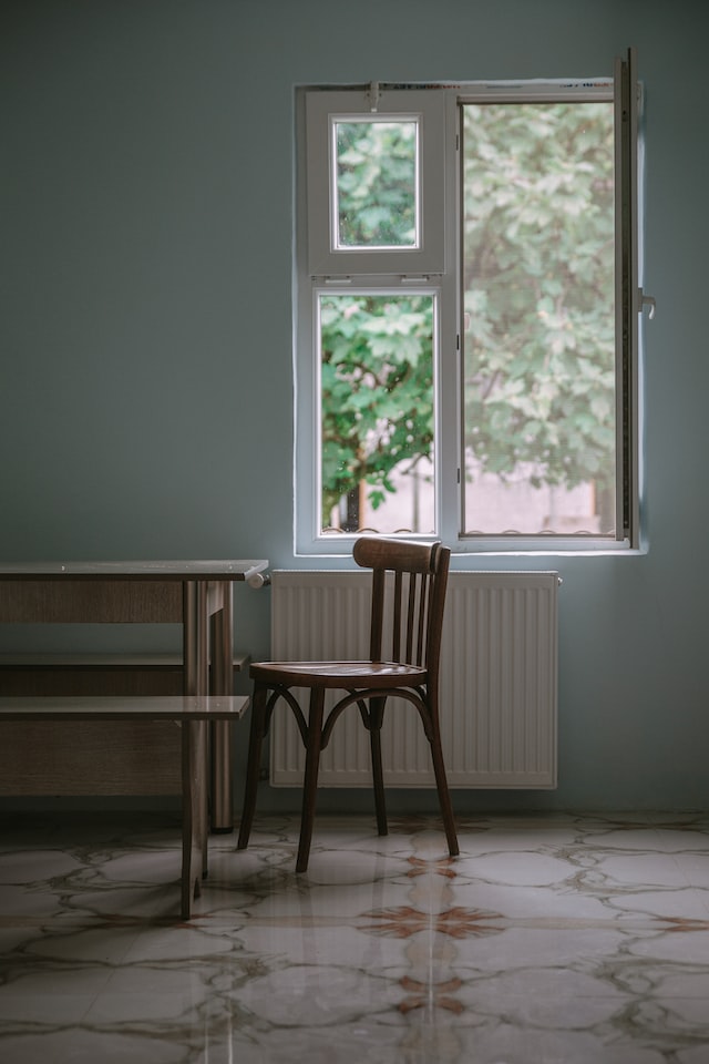 Ein Raum mit Tisch, Stuhl und einseitig geöffnetem Fenster