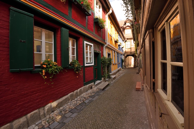 Eine kleine geziegelte Gasse geziert von niedrigen Häusern mit bunten Fensterläden