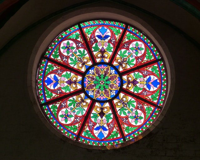 Ein rundes Fenster mit bunten Ornamenten durch das Licht fällt