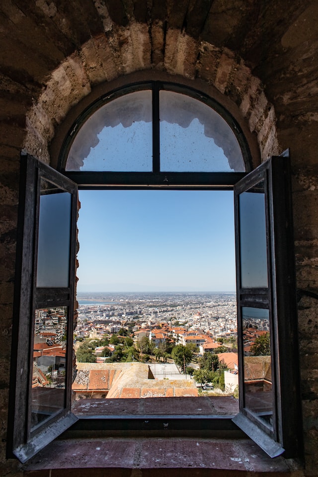 Ein Bogenfenster mit aufgeschlagenen Flügeln gibt den Blick nach Außen frei