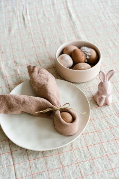 Kleine Naschereien dürfen zu Ostern nicht fehlen. Ein Ei, das mit einer Serviette umhüllt wurde, daneben noch mehr Eier