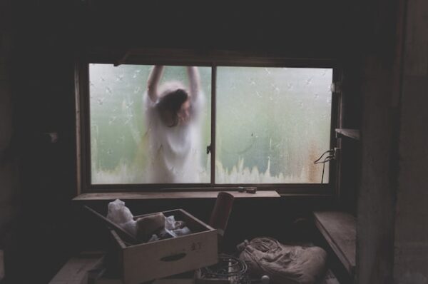 Eine Person hängt draußen am Rahmen eines Kellerfenster