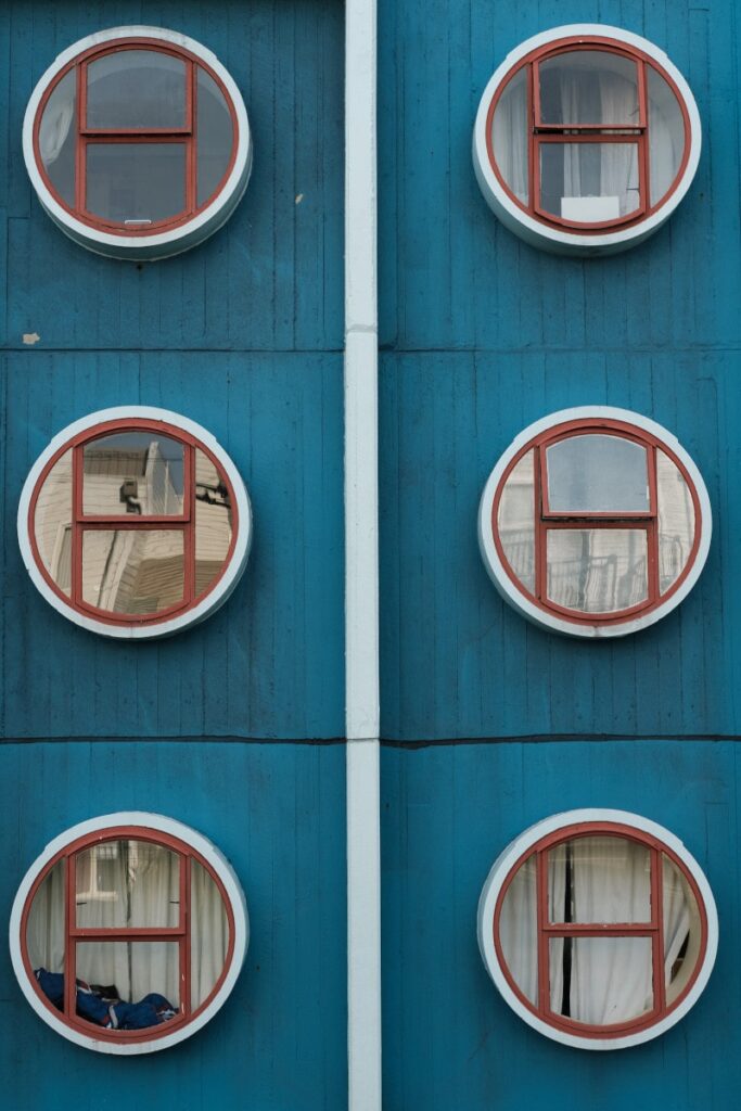 Einige verspiegelte, runde Fenster an einer blauen Fassade
