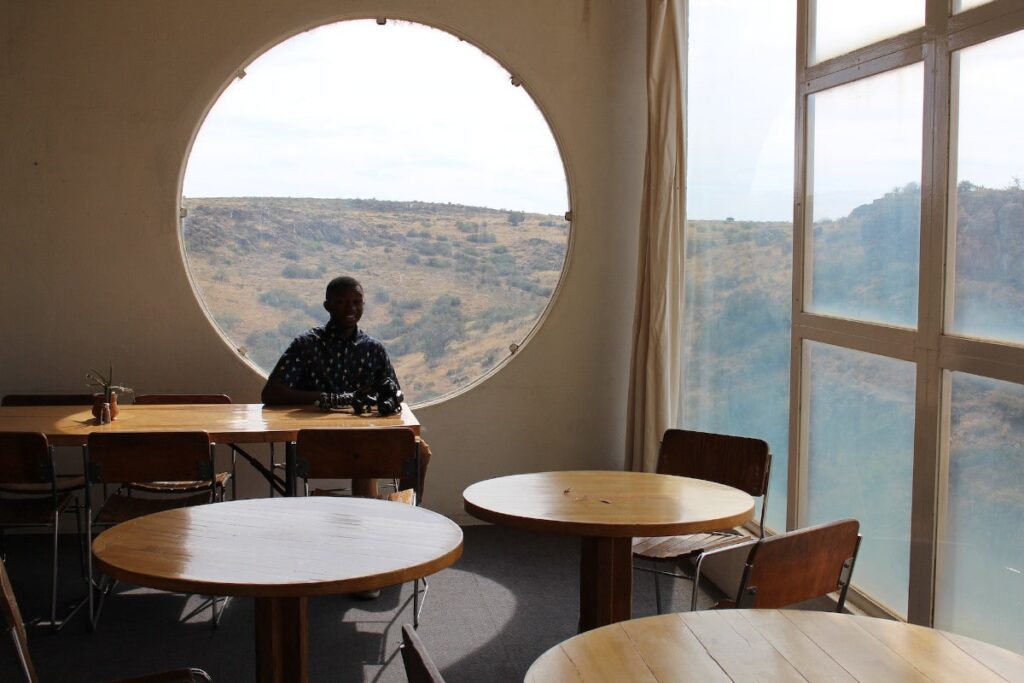 Ein Mann sitzt in einem Café vor einem runden Fenster