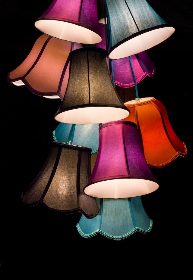 Mehrere Lampenschirme in unterschiedlichen Farben, die dicht über- und nebeneinander aufgehängt wurden