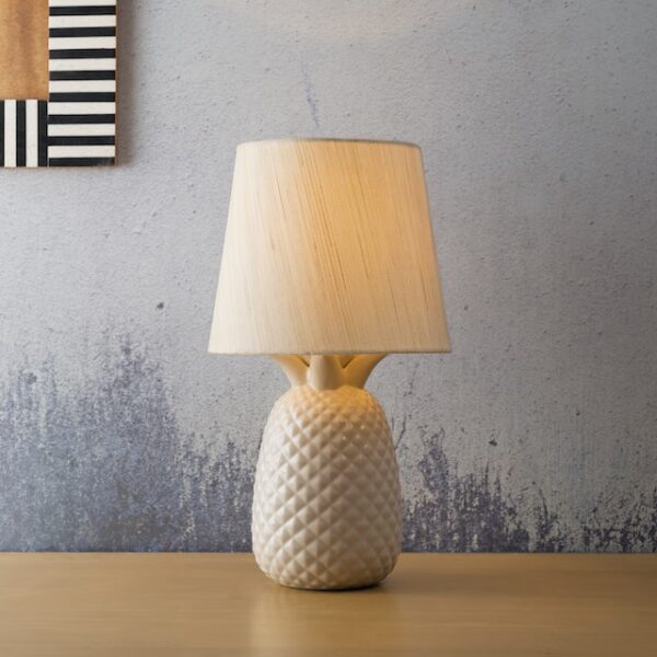 Eine Lampe mit hellem Schirm aus Stoff und Keramikbasis in Form einer Ananas