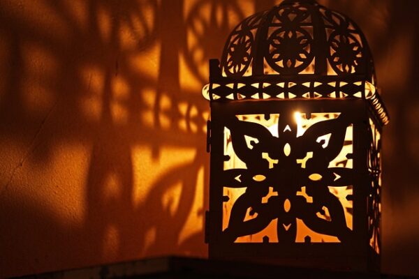 Ein schmaler Grat – Windlicht oder Laterne? Eine Laterne mit Muster wirft Schatten auf eine Wand