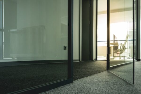 Für mehr Komfort und Ruhe beim Arbeiten Ein Büro mit Glastüren und dunklem Teppich