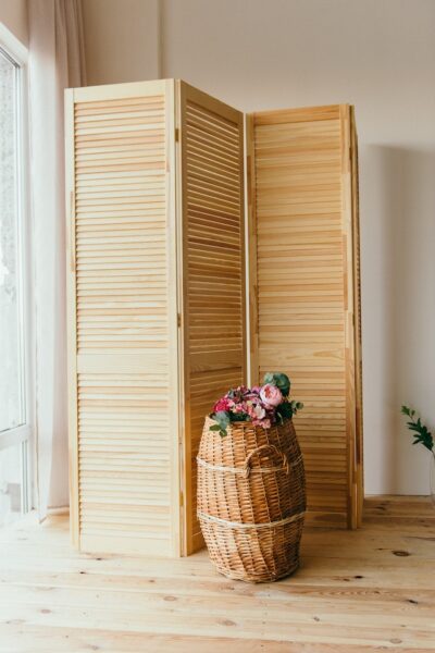 Eine schnelle und einfache Sichtschutz-Idee am Balkon: der Paravent Eine aufgestellte Sichtschutzwand aus hellem Holz, davor ein dekorativer Korb